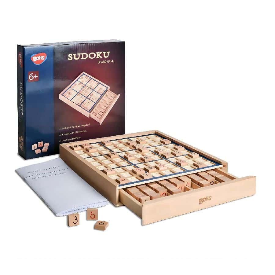 Scatola del Sudoku BOHS accanto alla tavoletta in legno con griglia 9x9, cassetto aperto con le tessere numerate e il libretto dei puzzle
